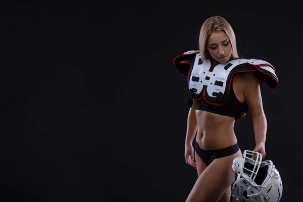 Attractive female american football player in uniform posing with helmet. girl sportswoman. Gender equality. Copy space