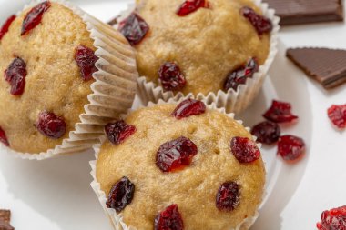 Ev yapımı kek kiraz ile hafif bir arka plan üzerinde yer alır. Bir kaç top kek beyaz bir tabak ön planda yer alan.