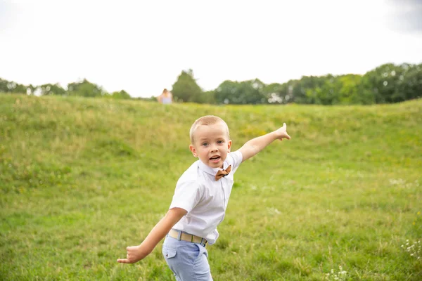 Un niñito lindo se sienta en la hierba — Foto de Stock