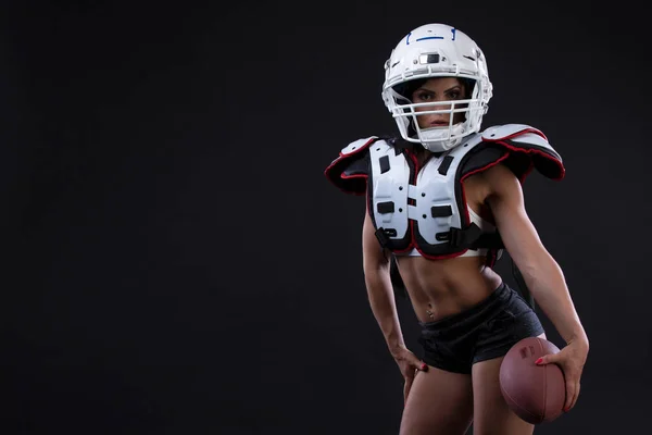 Spor kıyafeti güçlü kask ile rugby için seksi çekici genç kız portresi ileri siyah arka plan üzerinde duruyor. Kopya alanı