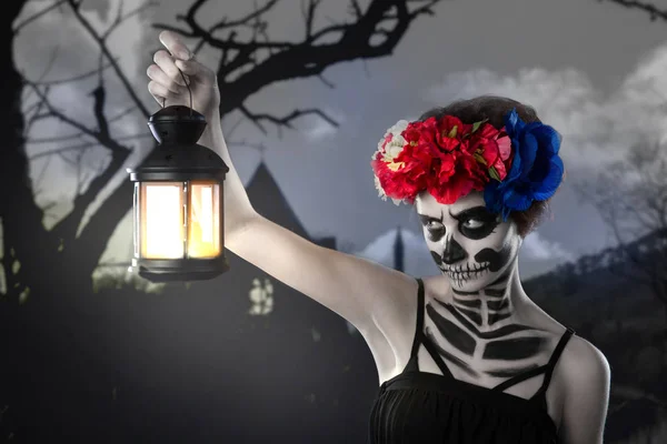 Bruja de Halloween. Hermosa mujer con máscara de santa muerte hechizo de lanzamiento cerca de la bombilla — Foto de Stock