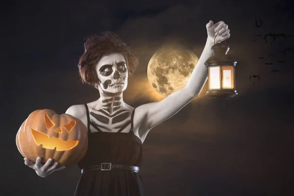 Retrato de mujer con esqueleto de Halloween maquillaje celebración de calabaza y lámpara — Foto de Stock