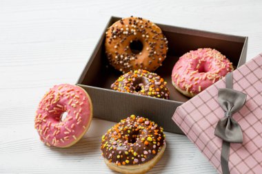 Beyaz ahşap zemin üzerinde bir kutu içinde sprinkles ile renkli lezzetli börekler