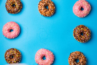 Kopya alanı mavi beton zemin üzerine Üstten Görünüm çeşitli Donuts. Renkli donut arka plan. Sprinkles ile çeşitli sırlı çörek.