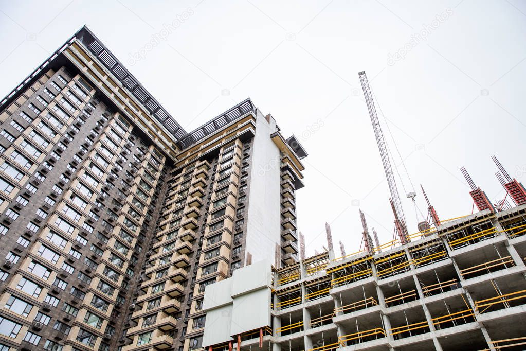 Construction site. Big industrial tower cranes with unfinished high raised buildings and blue sky in background. Scaffold. Modern civil engineering. Contemporary urban landscape.