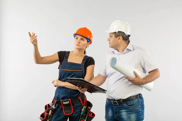 Un arquitecto con un sombrero duro o casco y una mujer constructora de compañeros de trabajo revisando planos — Foto de Stock