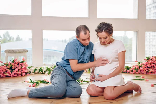Mujer embarazada feliz con su marido están sosteniendo y escuchando al bebé en el vientre y el establecimiento en el piso de las salas de estar en casa, embarazada y concepto familiar —  Fotos de Stock