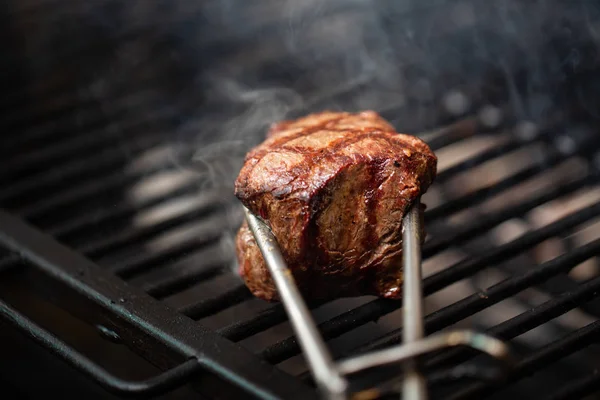 トングを保持は 豚カルビを焼き 背景に熱い燃えるようなバーベキュー グリル Rastaurant の料理 — ストック写真