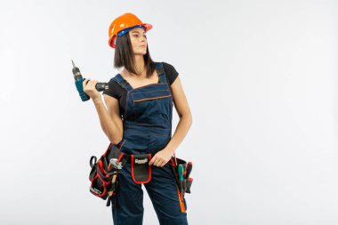 Evde çalışma için matkap ve bazı güç araçlarını kullanarak toolbelt olan kadın. Düz beyaz arka plan üzerinde remodeling çalışan kız. Bina, onarım ve yenileme.