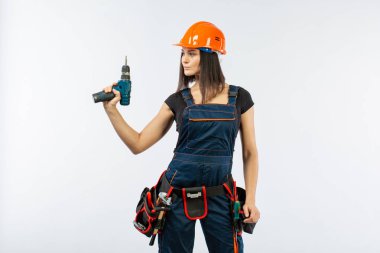 Evde çalışma için matkap ve bazı güç araçlarını kullanarak toolbelt olan kadın. Düz beyaz arka plan üzerinde remodeling çalışan kız. Bina, onarım ve yenileme.