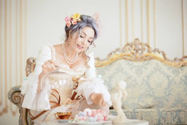 Kahvaltı yemek yerken pembe bir arka plan önünde poz Rokoko içinde güzel greyhead kadın. Cadılar Bayramı