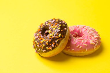 çikolata ve pembe çörek sarı bir arka plan üzerinde yalan. kopya alanı