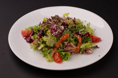 Unagi salata somon içerir domates, susam, marul yaprakları beyaz tabakta. Japon yemekleri