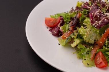 Unagi salata somon içerir domates, susam, marul yaprakları beyaz tabakta. Japon yemekleri