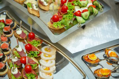 Tablo küme hizmeti çeşitli atıştırmalıklar şölende bir masada yemek servisi. Soğuk aperatifler, kanepe, içecekler, closeup kümesi. Yan görünüm.