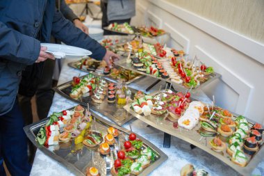 Yemek masası, ziyafette sofraya çeşitli atıştırmalıklar koydu. Soğuk aperatifler, kanepeler, içecekler, yakın çekim. Yan görüş. Ziyafet masası.