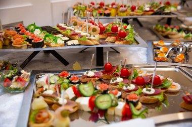 Yemek masası, ziyafette sofraya çeşitli atıştırmalıklar koydu. Soğuk aperatifler, kanepeler, içecekler, yakın çekim. Yan görüş. Ziyafet masası.