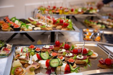 Yemek masası, ziyafette sofraya çeşitli atıştırmalıklar koydu. Soğuk aperatifler, kanepeler, içecekler, yakın çekim. Yan görüş. Ziyafet masası.