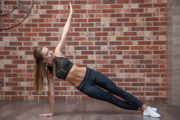 Vacker ung kvinna som gör övningar på golvet för att stärka hennes muskler, studio porträtt — Stockfoto