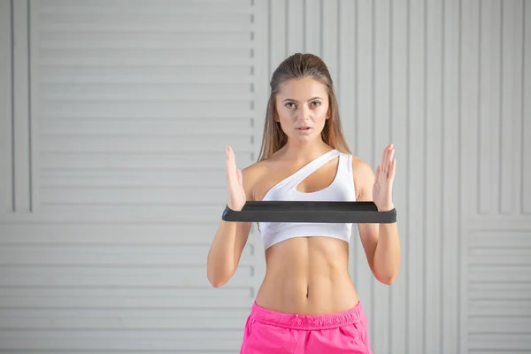 Fitness young woman doing back exercise with resistance band for training strength. Female athete exercising at studio