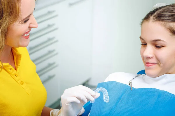 Gros plan d'une main de dentiste montrant un implant à un patient dans un bureau — Photo