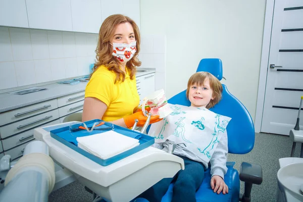 Dentista ensinando menino como limpar os dentes na clínica odontológica — Fotografia de Stock