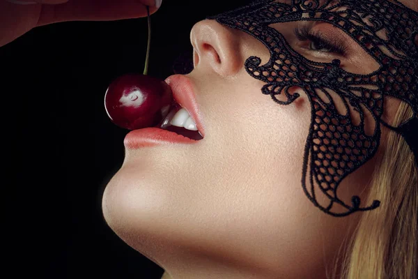 Detail van jonge vrouw mond met kersen tegen zwarte achtergrond. — Stockfoto