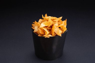 Bir kase içinde patates cipsi. Bir yığın bir kase içinde yığılı patates cips. Yemek bir siyah arka plan üzerine oturuyor.