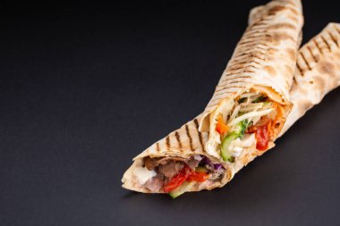Shawarma sandviç - taze rulo ince lavaş veya pide ekmek ızgara et, mantar, peynir, lahana, havuç, sosu, yeşil ile dolu. Geleneksel Doğu Aperatif. Siyah bir arka plan üzerinde.