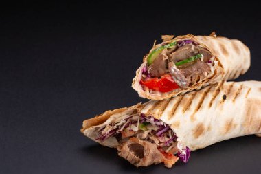 Shawarma sandviç - taze rulo ince lavaş veya pide ekmek ızgara et, mantar, peynir, lahana, havuç, sosu, yeşil ile dolu. Geleneksel Doğu Aperatif. Siyah bir arka plan üzerinde.