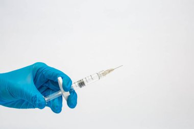 Doktor eldiven içinde bir el bir şırınga ward önünde tutar.