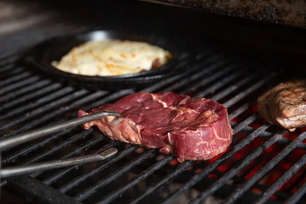 鉗子のクローズ アップ ビューと熱いグリル料理に新鮮な肉 — ストック写真