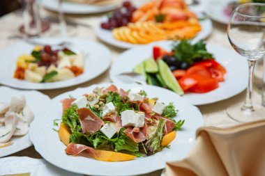 Taze karışımı jambon, beyaz peynir ve beyaz tabakta mango salatası. Restoran Tablo ayarı