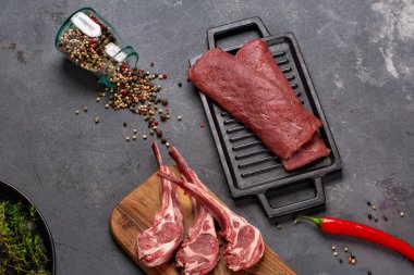 Baharat Chesno kemikte et çiğ taze koyun eti ve siyah bir zemin üzerine biberiye