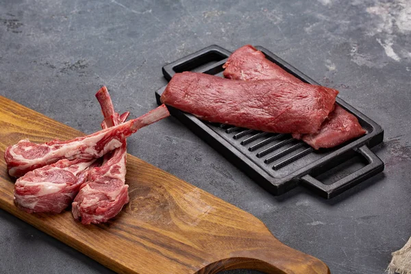 Carne di montone fresco crudo sull'osso Spezie Chesno e rosmarino su fondo nero — Foto Stock