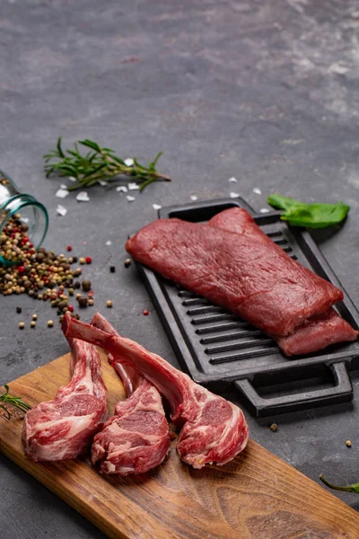 Vlees rauw vers vlees van schapen op het bot specerijen Chesno en rozemarijn op een zwarte achtergrond — Stockfoto