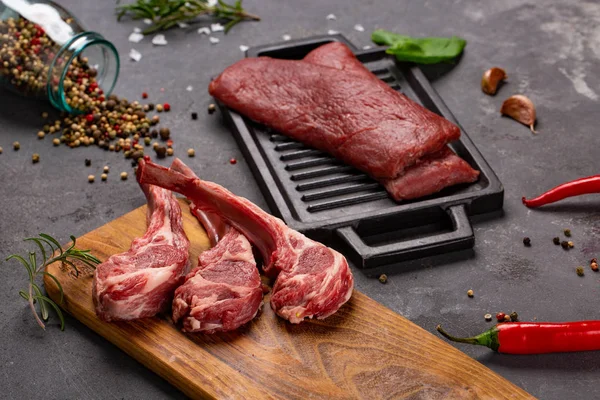 Vlees rauw vers vlees van schapen op het bot specerijen Chesno en rozemarijn op een zwarte achtergrond — Stockfoto