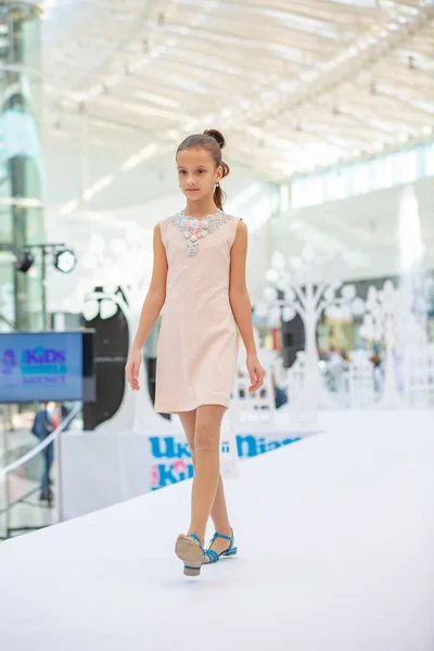 Kiev, Ucrania marzo 03.2019. UKFW. Día de la moda de niños ucranianos. Pequeña modelo de niña vestida con vestido pastel posando en el podio — Foto de Stock
