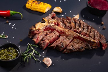 porterhouse biftek ızgara biftek ızgara mısır, sos, biber, biberiye, tuz, sarımsak siyah arka plan üzerine bir parça dilimlenmiş. rustik tarzı