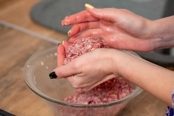 Raw minced meat in slender woman's hands