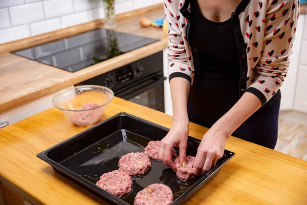Young woman cooking meatballs or cutlets in modern kitchen