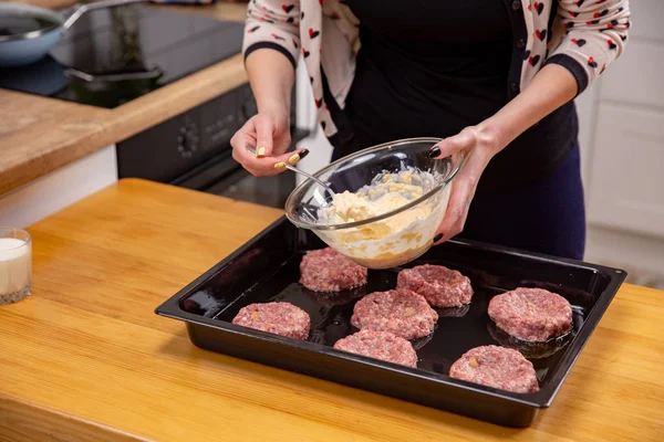 Женская рука накладывает фаршированное мясо или фрикадельки, лежащие на черном подносе для выпечки. Процесс приготовления пищи . — стоковое фото