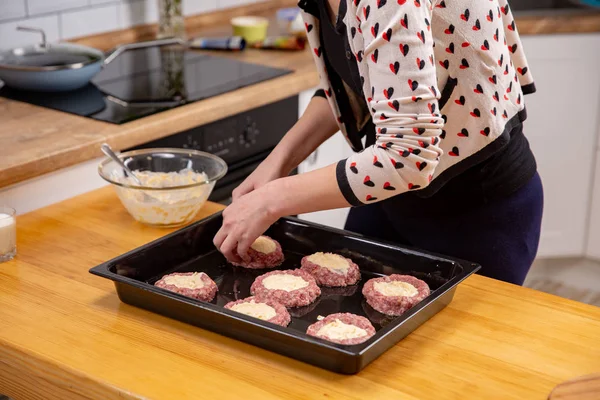 Женская рука накладывает фаршированное мясо или фрикадельки, лежащие на черном подносе для выпечки. Процесс приготовления пищи . — стоковое фото
