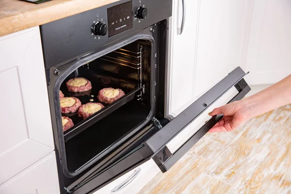 Close up of women hand opening the oven door to control the roast — Stock Photo, Image