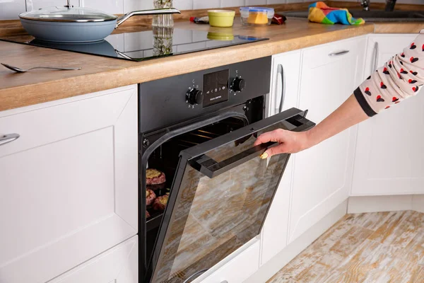 Close up of women hand opening the oven door to control the roast — Stock Photo, Image