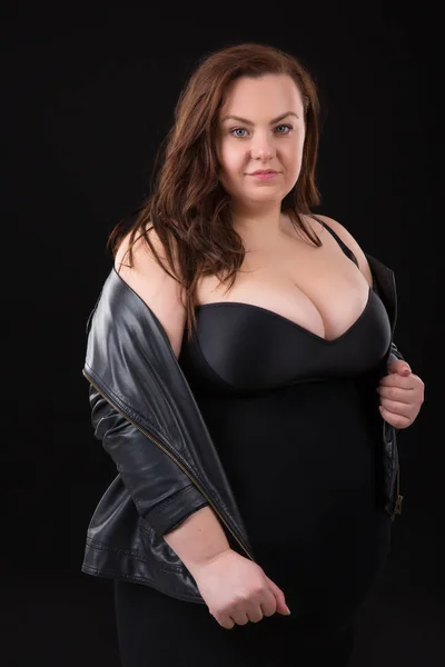 Hermosa mujer joven más tamaño con busto grande en ropa interior y chaqueta de cuero n fondo negro —  Fotos de Stock