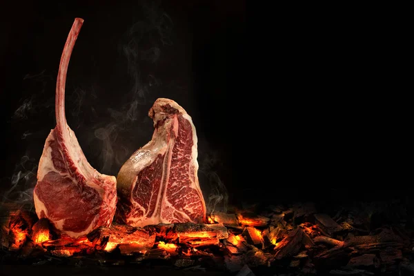 Bütün T-Bone biftek köz üzerinde yemek. Siyah arka plan.