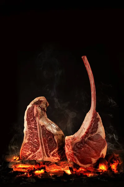 Bütün T-Bone biftek köz üzerinde yemek. Siyah arka plan.