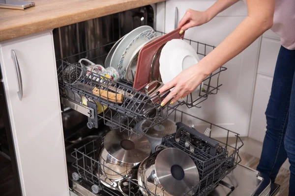 Женская рука кладет белую тарелку в посудомоечную машину домашнюю работу — стоковое фото