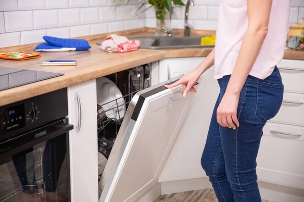 Diska i diskmaskinen. Kvinnan sätter smutsig disk i diskmaskinen. Öppning och stängning diskmaskinen. — Stockfoto